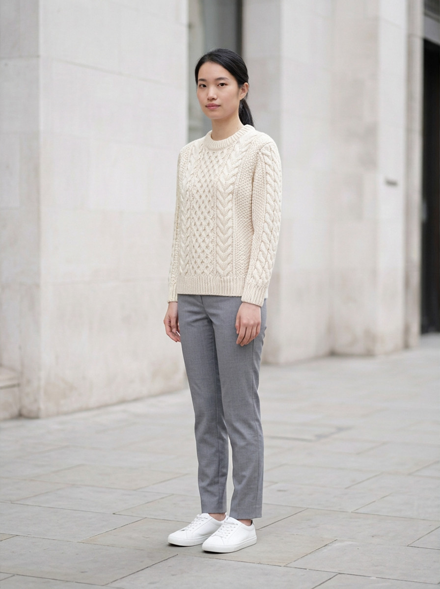 Cream chunky cable knit sweater, three-quarter view, outdoor daylight street
